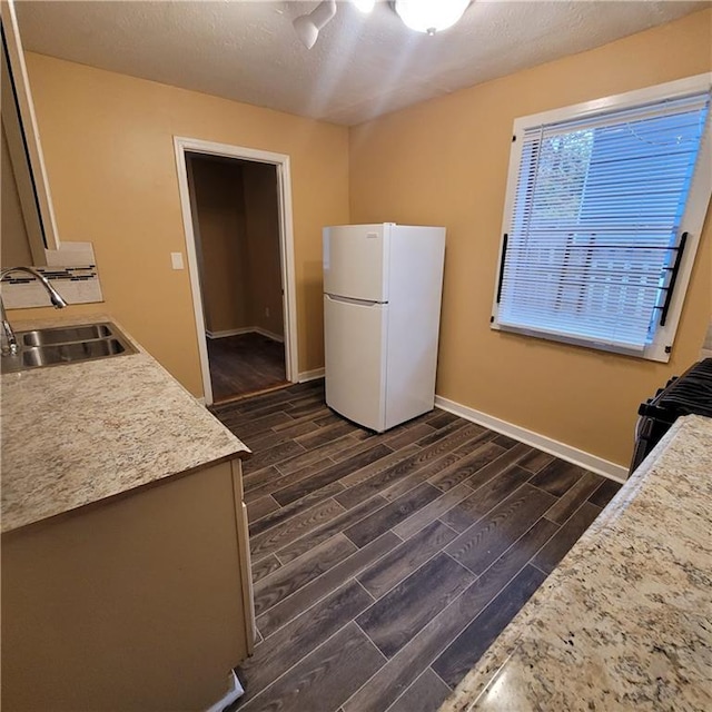 kitchen with baseboards, wood tiled floor, freestanding refrigerator, a sink, and light countertops