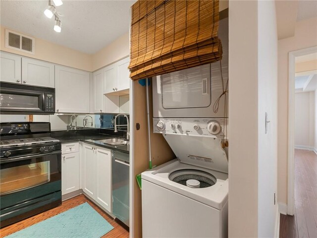2479 Peachtree Rd NE Unit 407, Atlanta, GA 30305 - kitchen featuring black appliances, a sink, stacked washer / dryer, and white cabinets