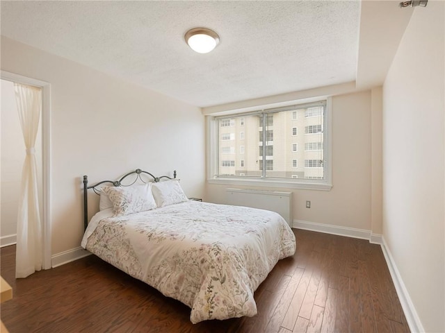 2479 Peachtree Rd NE Unit 407, Atlanta, GA 30305 - bedroom featuring a textured ceiling, dark wood finished floors, baseboards, and radiator heating unit