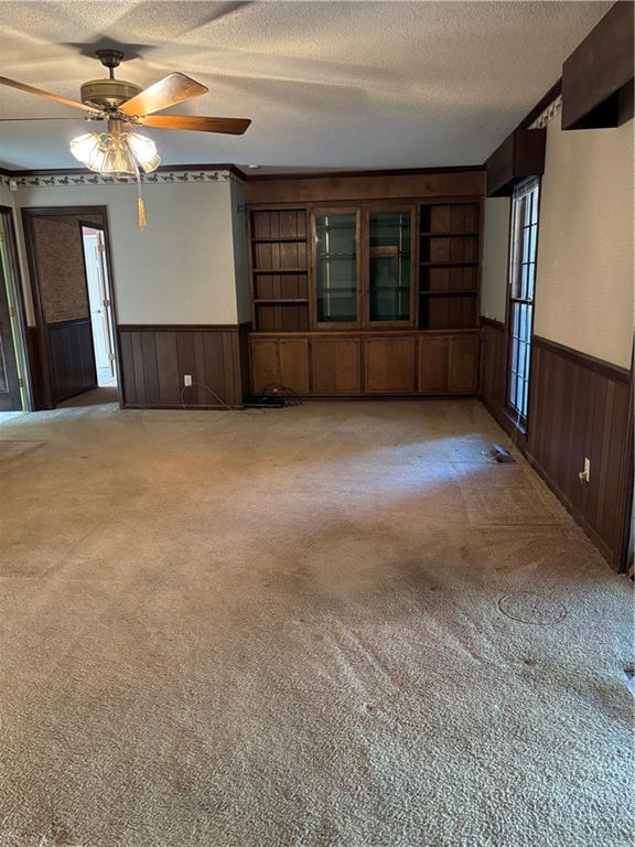 carpeted empty room featuring ceiling fan and a textured ceiling