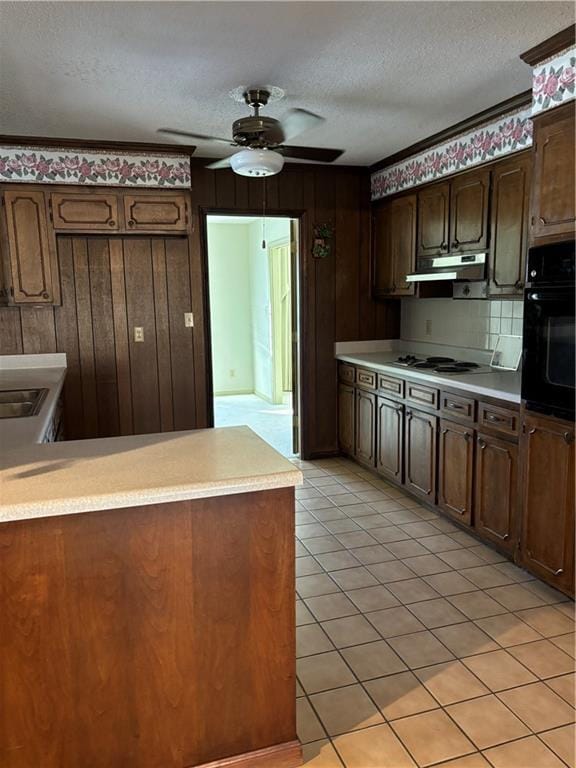 kitchen featuring light tile patterned floors, white cooktop, black oven, ceiling fan, and a textured ceiling