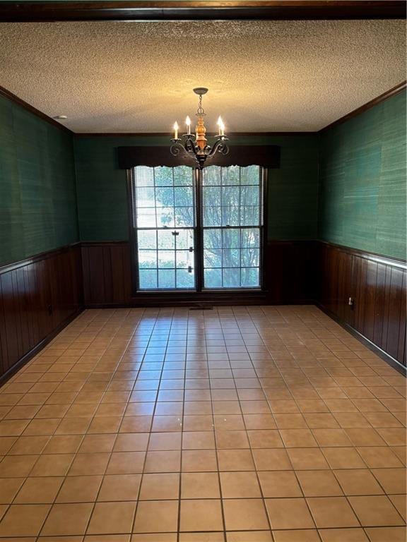 empty room featuring light tile patterned floors, an inviting chandelier, and a textured ceiling