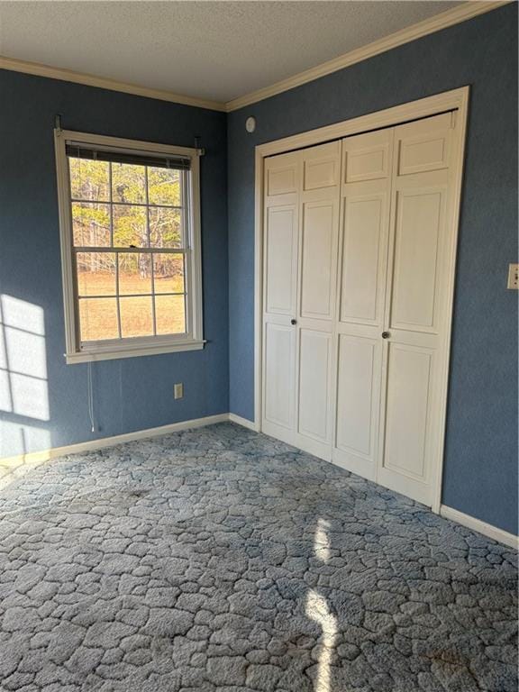 unfurnished bedroom featuring a textured ceiling, a closet, and ornamental molding