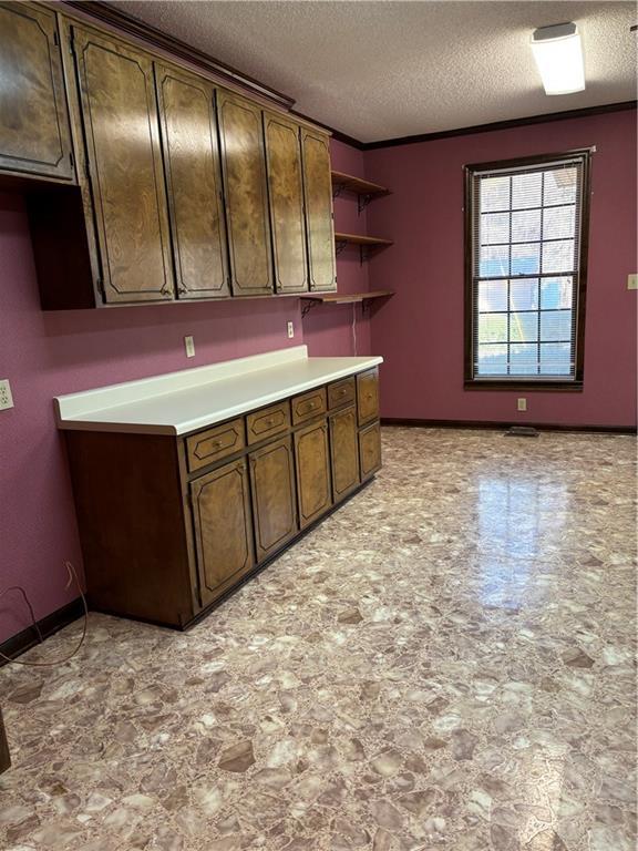 kitchen with a textured ceiling and dark brown cabinetry