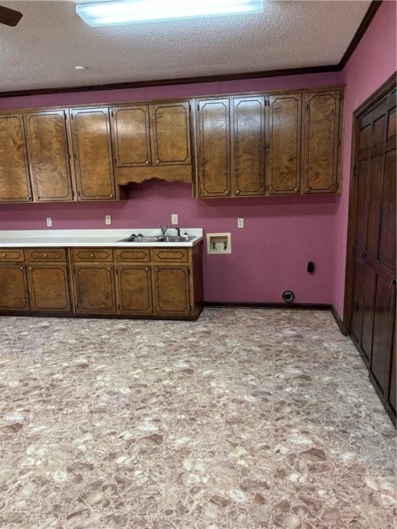 kitchen featuring sink, a textured ceiling, and ornamental molding