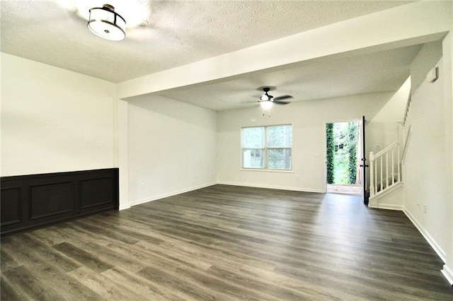 unfurnished living room with dark hardwood / wood-style flooring, ceiling fan, and a textured ceiling