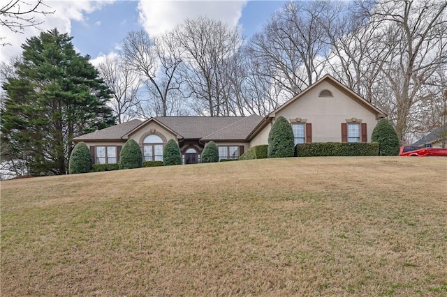 view of front of home with stucco siding, a front yard, and roof with shingles