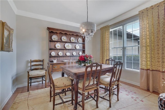 dining area with light wood finished floors, baseboards, crown molding, and an inviting chandelier