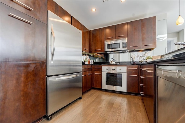 kitchen with stainless steel appliances, light hardwood / wood-style floors, and decorative light fixtures