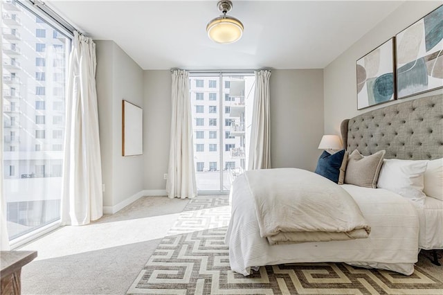 bedroom with light colored carpet, multiple windows, and access to outside
