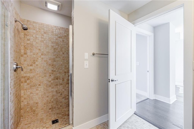 bathroom with tiled shower and wood-type flooring