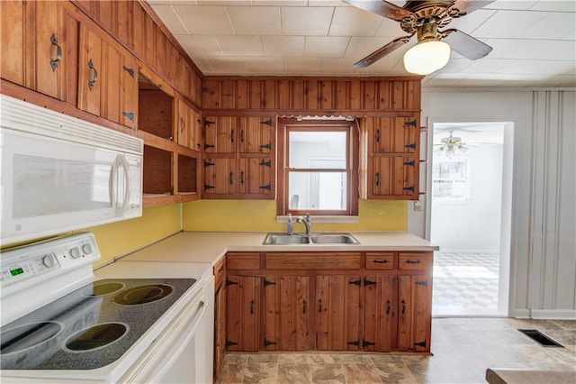 kitchen featuring white appliances, visible vents, brown cabinetry, light countertops, and a sink