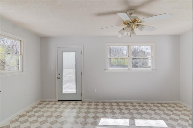 doorway featuring a textured ceiling, light floors, and baseboards