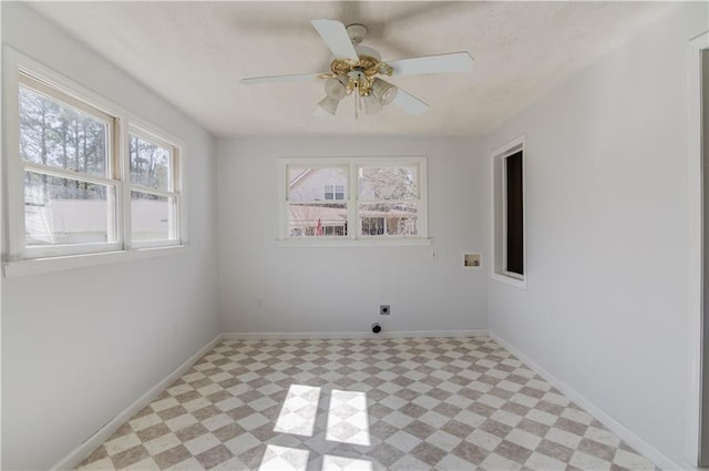 spare room featuring light floors, a ceiling fan, and baseboards