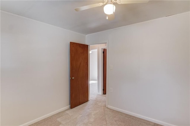 empty room with baseboards, a ceiling fan, and light colored carpet