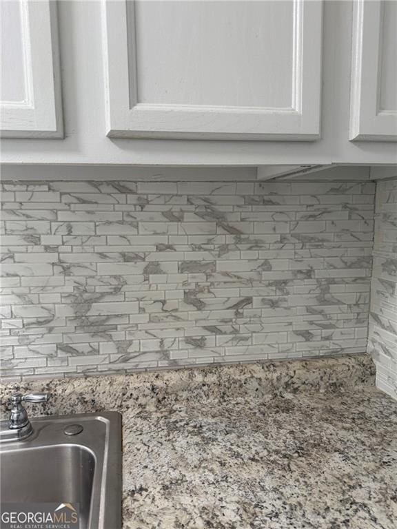 5770 Satterfield Dr, Macon, GA 31206 - kitchen view of backsplash, white cabinetry, and light stone countertops