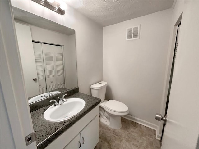 bathroom featuring vanity, toilet, and a textured ceiling