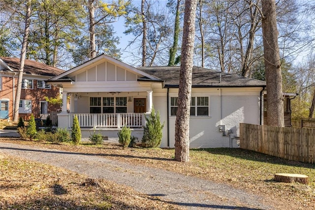 view of front of house featuring fence, a porch, board and batten siding, and brick siding