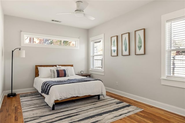 bedroom with a ceiling fan, baseboards, visible vents, and wood finished floors