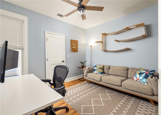 home office featuring a ceiling fan, visible vents, baseboards, and wood finished floors