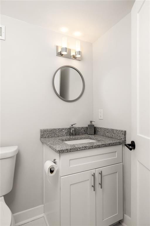 half bathroom featuring baseboards, vanity, and toilet