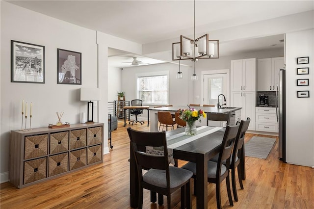 dining room featuring ceiling fan with notable chandelier and light wood-style flooring