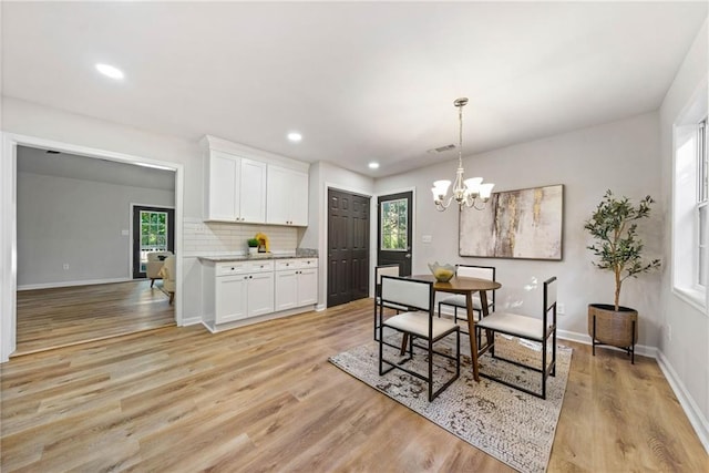 dining area with light hardwood / wood-style floors, an inviting chandelier, and a wealth of natural light