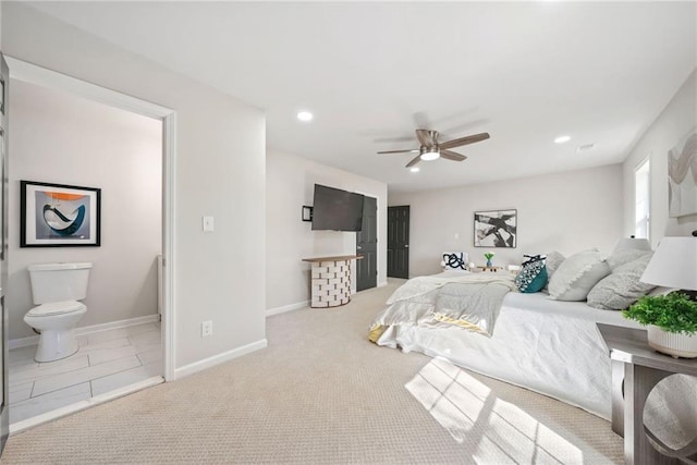 bedroom with ensuite bath, light carpet, and ceiling fan