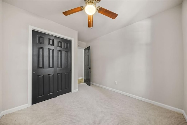 unfurnished bedroom featuring light colored carpet, a closet, and ceiling fan