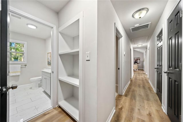 hall featuring light wood-type flooring and built in shelves