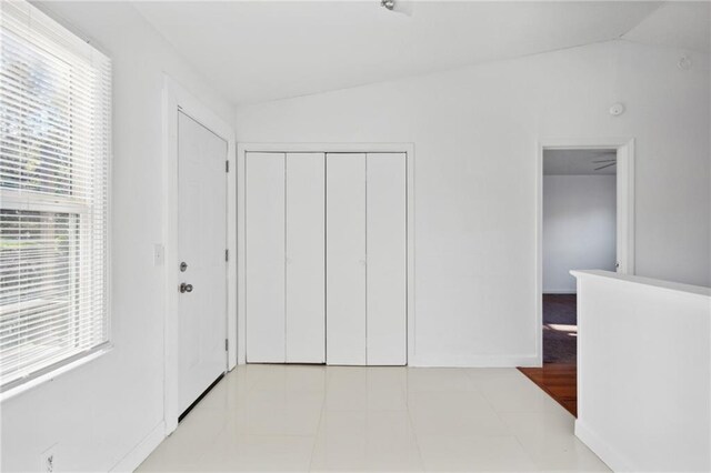 bedroom featuring a closet, multiple windows, lofted ceiling, and light tile patterned floors