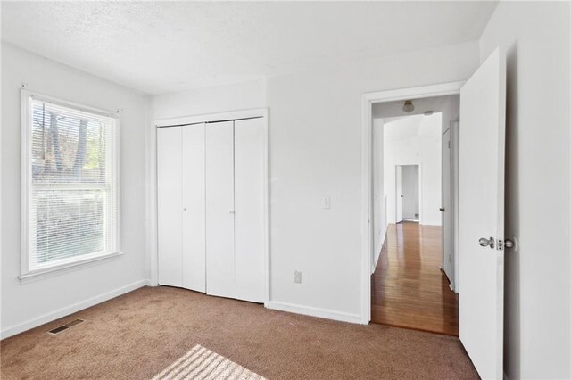 unfurnished bedroom with light carpet and a closet