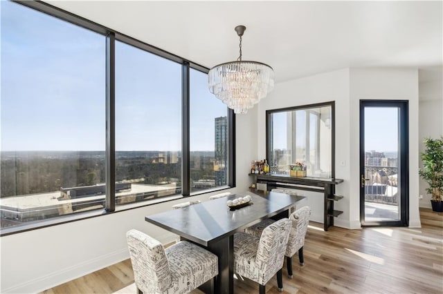 dining space featuring light wood-style floors, a view of city, and an inviting chandelier