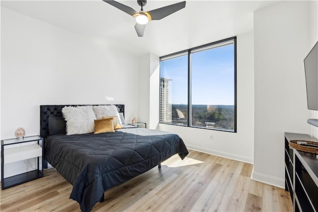 bedroom featuring ceiling fan, light wood-style flooring, and baseboards