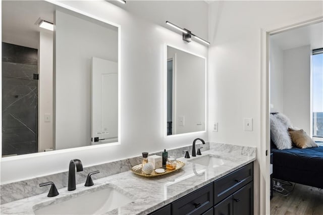 ensuite bathroom featuring ensuite bathroom, double vanity, wood finished floors, and a sink