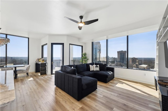 living room with a view of city, plenty of natural light, baseboards, and light wood-style floors