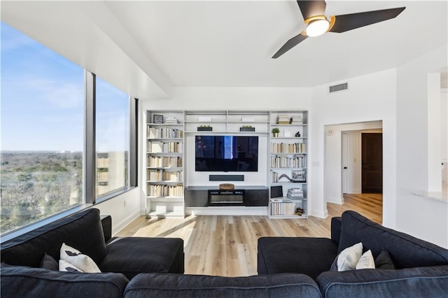 living room with light wood-type flooring, ceiling fan, and visible vents