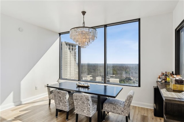 dining room featuring light wood-style floors, baseboards, and a notable chandelier