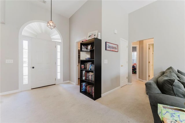 foyer featuring baseboards, a high ceiling, and light colored carpet