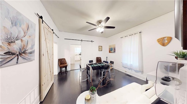 interior space with ceiling fan, a barn door, dark hardwood / wood-style flooring, and a healthy amount of sunlight