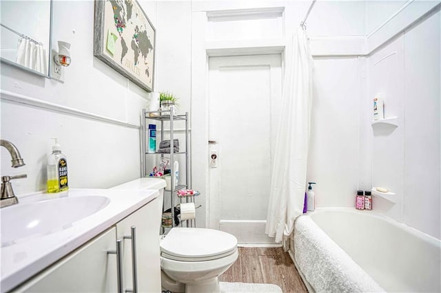 full bathroom with hardwood / wood-style floors, vanity, shower / tub combo, and toilet