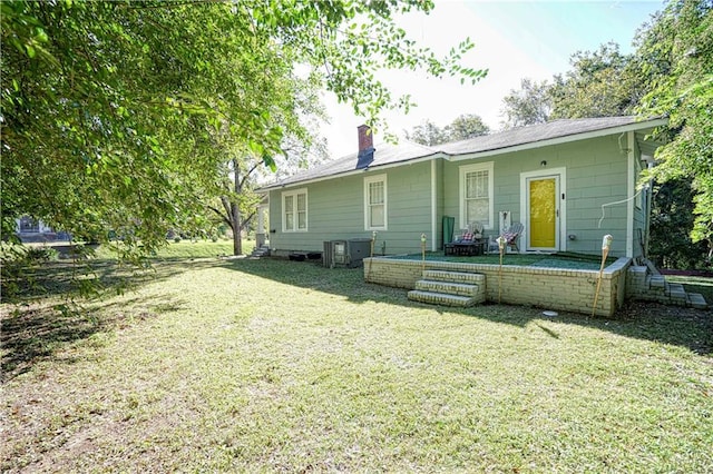 back of house featuring central air condition unit and a lawn