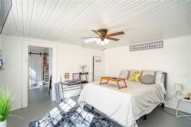 bedroom featuring concrete floors, ceiling fan, and a barn door