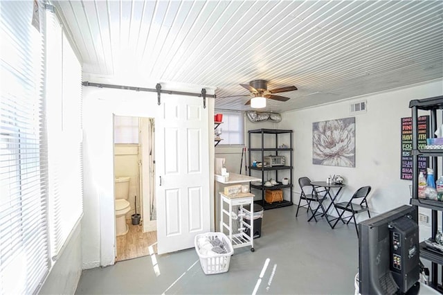 interior space featuring concrete flooring, a barn door, and ceiling fan