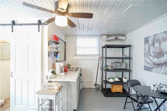 interior space with ceiling fan, a barn door, wood ceiling, and sink