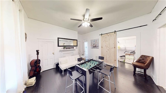 game room with a barn door, ceiling fan, and dark hardwood / wood-style flooring