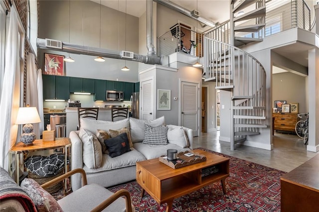 living room with stairs, a high ceiling, visible vents, and baseboards