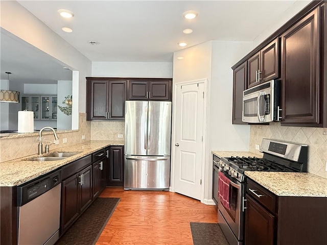 5850 Shiloh Woods Dr, Cumming, GA 30040 - kitchen with appliances with stainless steel finishes, a sink, backsplash, dark brown cabinets, and light stone countertops