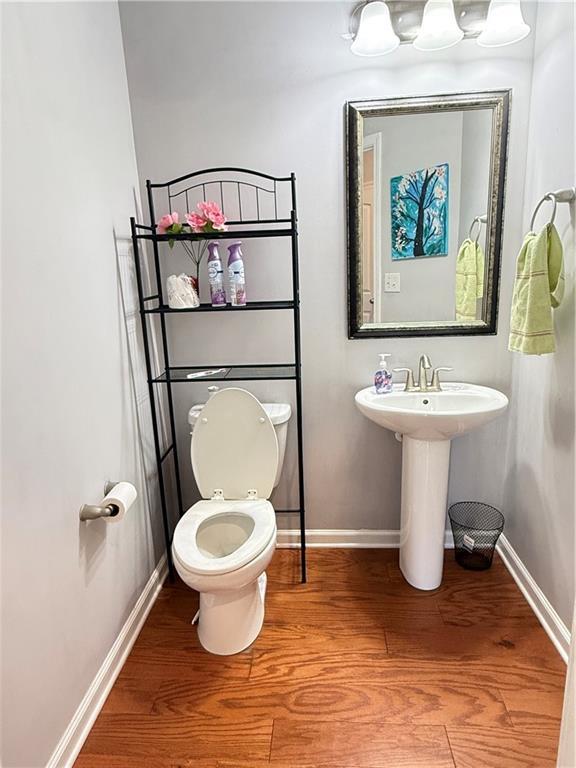 5850 Shiloh Woods Dr, Cumming, GA 30040 - half bathroom featuring wood finished floors, baseboards, toilet, and a sink