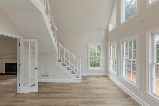 unfurnished living room with a healthy amount of sunlight, high vaulted ceiling, and light wood-type flooring